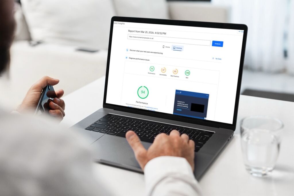 A person sitting at a desk using a laptop to view a website performance report, illustrating a technical health check for an Avada WordPress site.